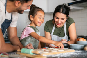 Happy girl baking at home with her loving parents