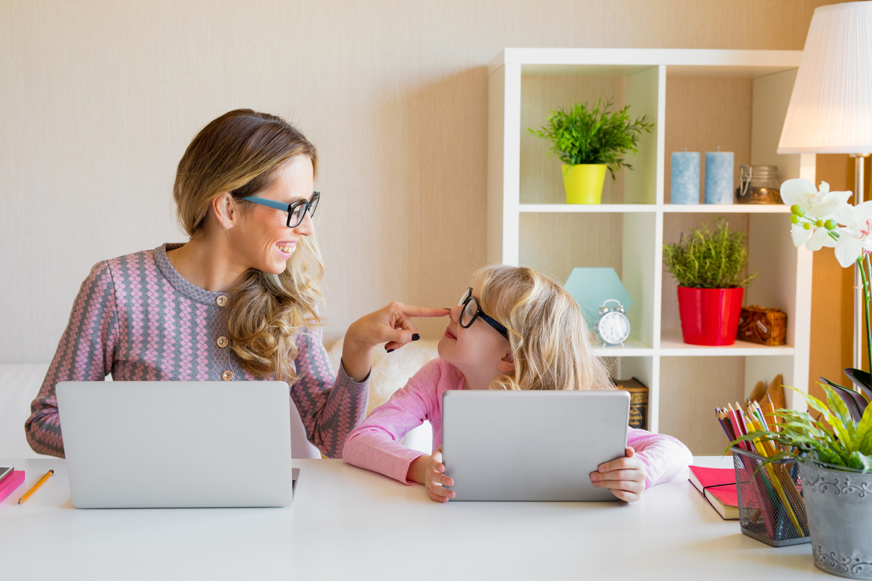 Mother and daughter sitting at table and using computers together