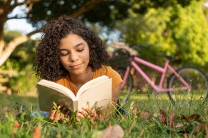 Teen girl lying on the grass reading a book